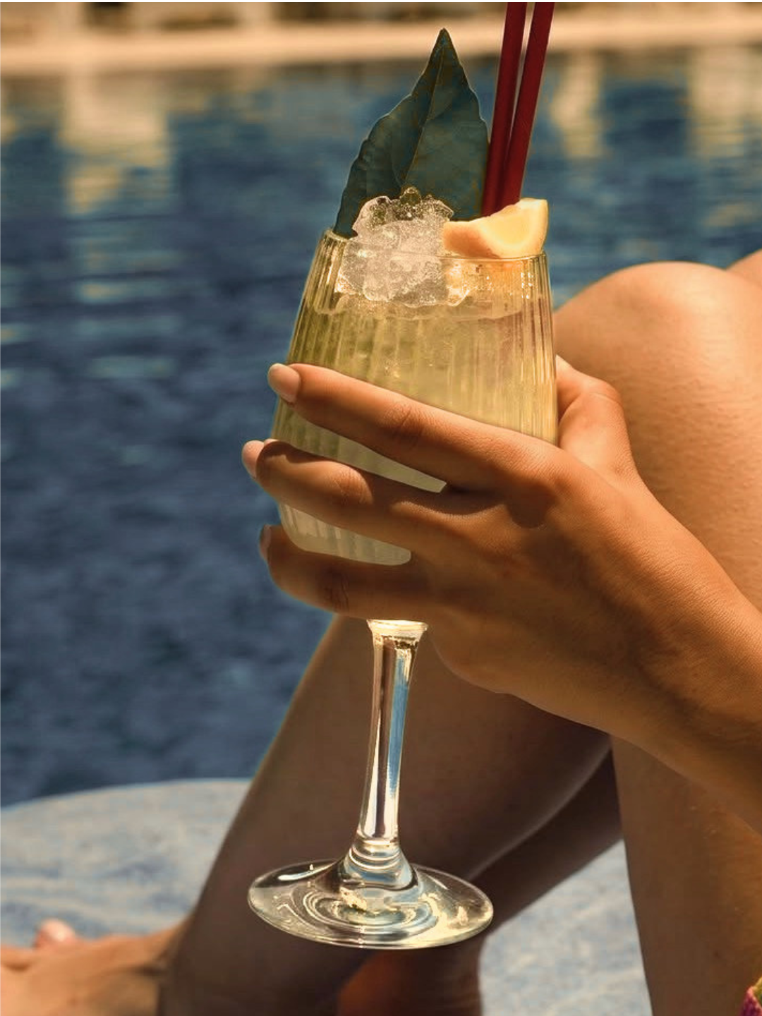 Prime champagne flute filled with sparkling wine on the stone edge of a pool overlooking a lake